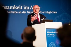 Dr. Schreiber, ein älterer Mann mit Halbglatze, einem dunklen Anzug, darunter weißes Hemd und roter Schlips, steht an einem Rednerpult und spricht gestikulierend. Klick öffnet eine vergrößerte Ansicht.