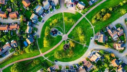 ©istock | Chunyip Wong Ein Luftaufnehmen. Ein begrünter Kreis, durch den eine Straße und Wege führen. Darum sind auch Wohnhäuser zu sehen.