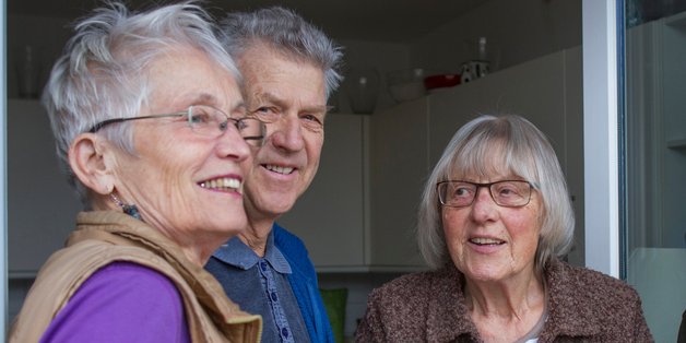 Zwei ältere Frauen und ein Mann stehen vor einer Terassentür.