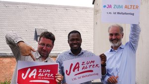 ©BAGSO Drei Männer stehen nebeneinander. Sie halten jeweils ein Schild in der Hand mit der Aufschrift "Ja zum Alter!" Einer von ihnen zeigt mit dem Zeigefinger auf das Schild.